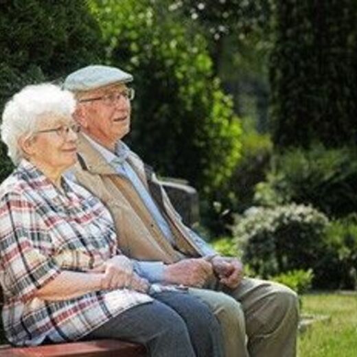 Altes Ehepaar sitzt im Park auf einer Bank