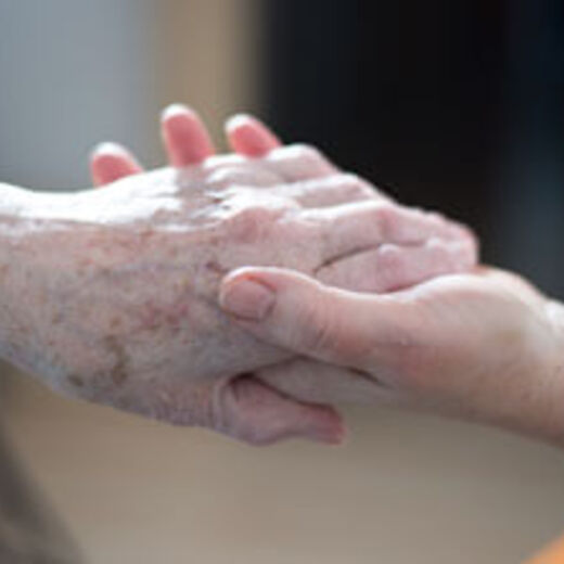 Eine ältere Person und eine junge Person geben sich die Hand