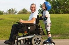 Mann im Rollstuhl wird von seinem Sohn mit Inlineskates geschoben