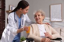 Den richtigen Pflegedienst suchen und finden: Eine Pflegerin bringt einem älteren Mann ein Tablett mit Essen und Trinken