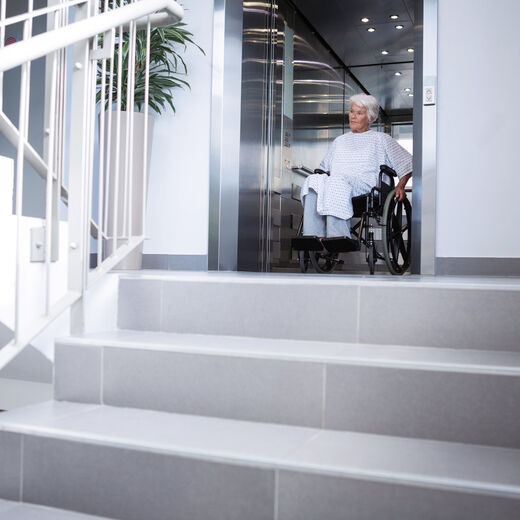 Seniorin im Rollstuhl fährt aus Behindertenlift