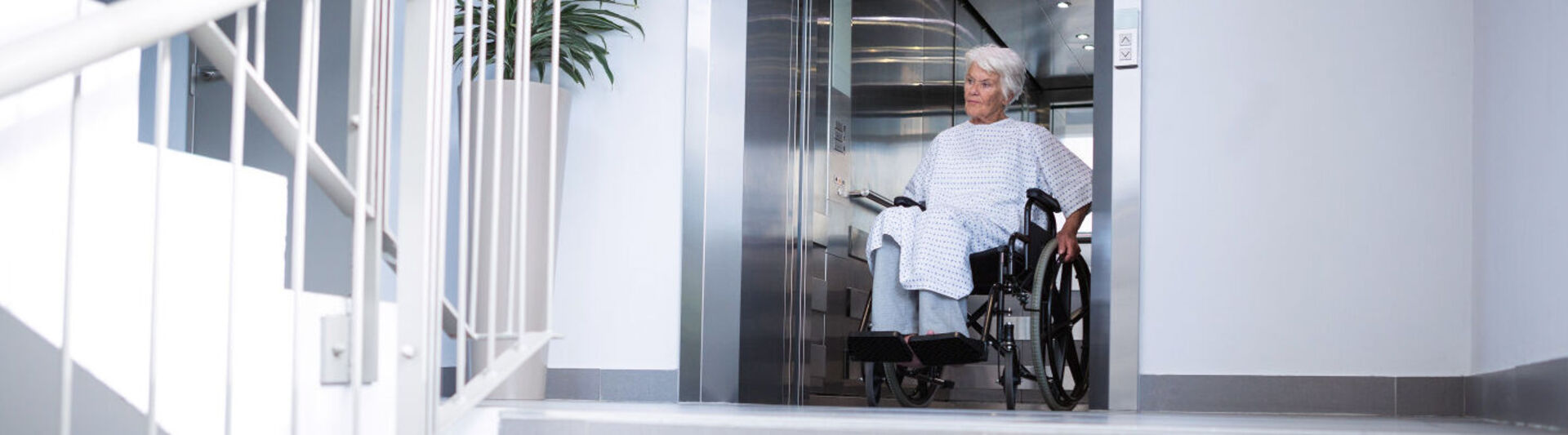 Rollstuhlfahrerin verlässt den Aufzug vom Krankenhaus