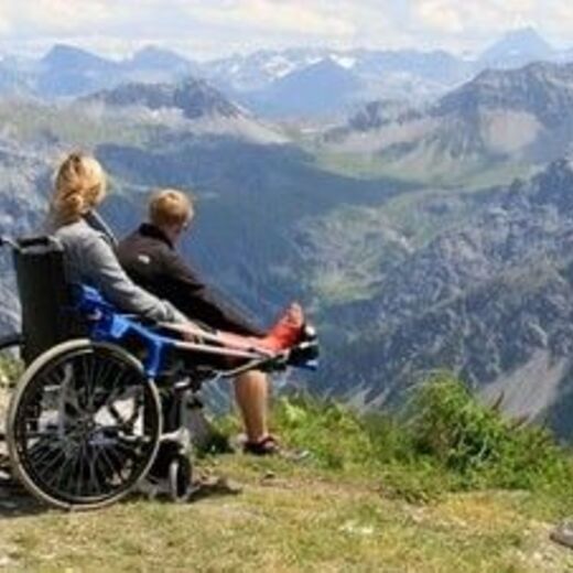 Rollstuhlfahrerin betrachtet die Berge