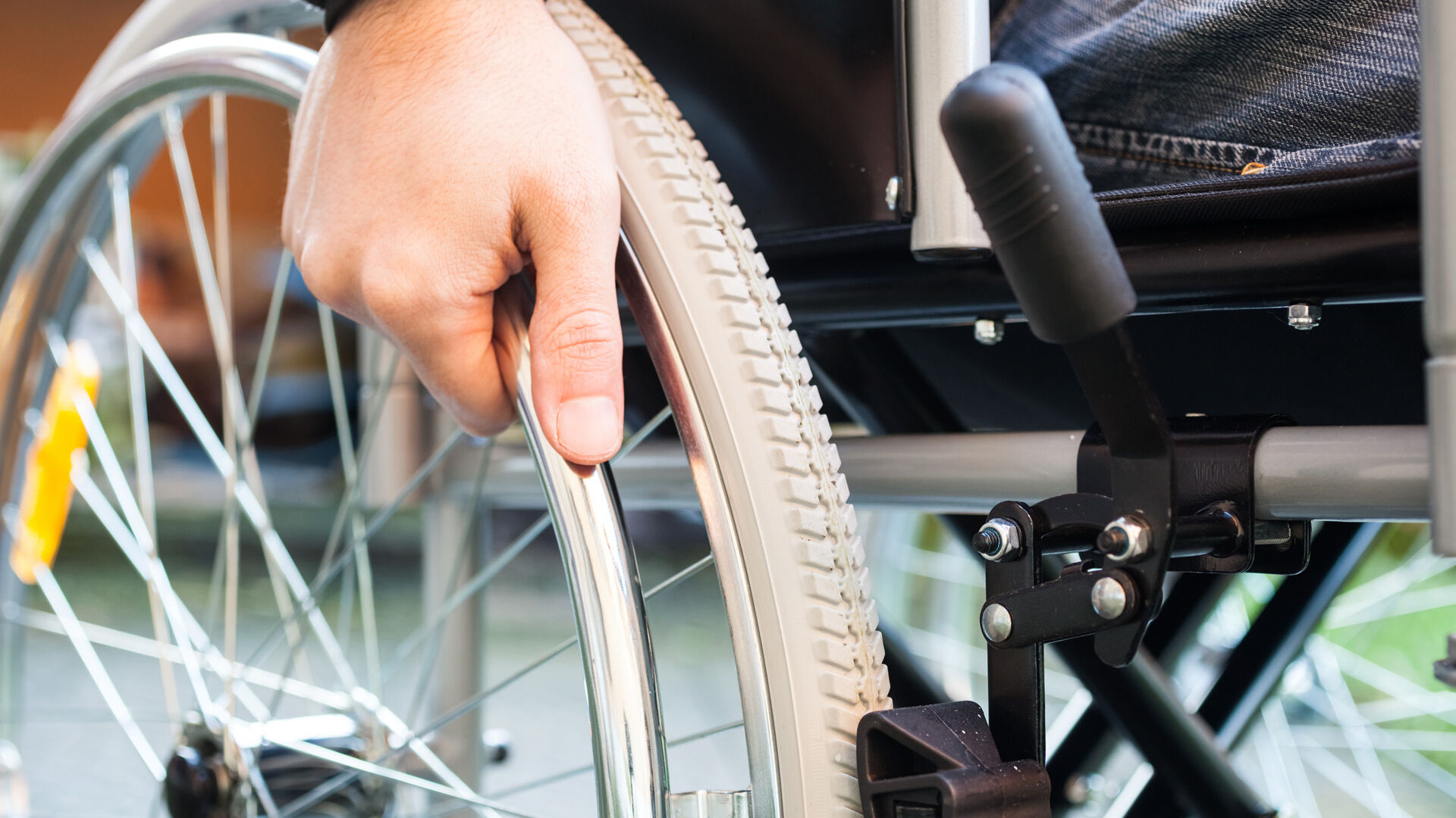 Treppenlifte können Rollstuhlfahrern helfen Eine Hand die das Rad vom Rollstuhl anschiebt