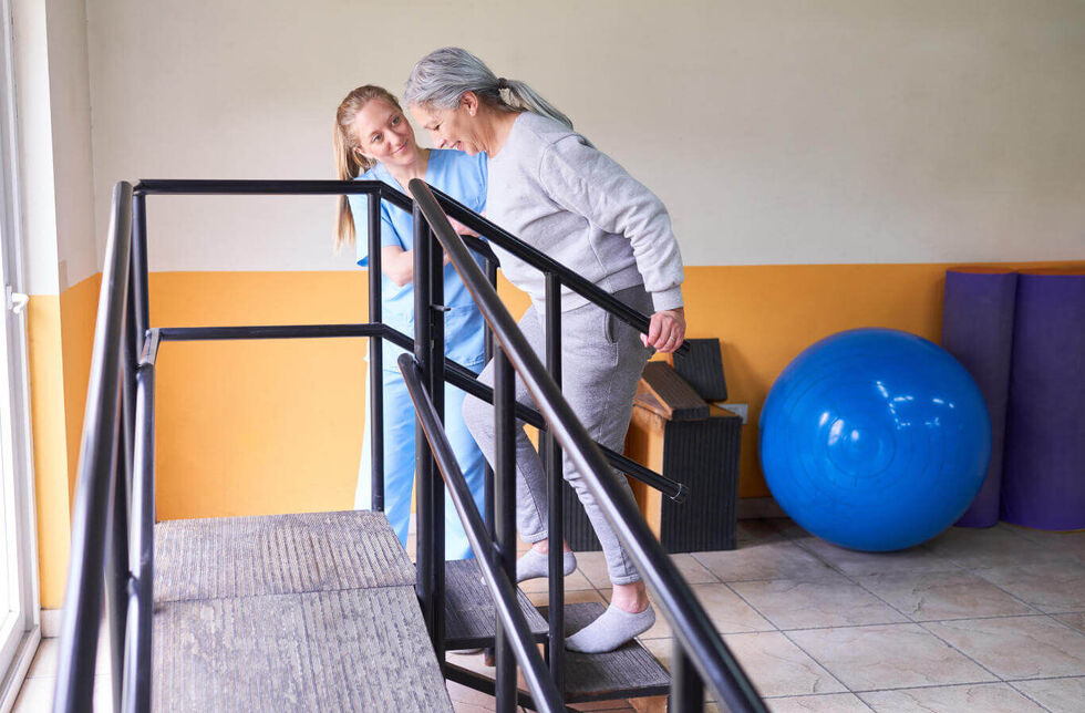 Physiotherapeutin unterstützt Seniorin beim Treppensteigen. © Robert Kneschke - stock.adobe.com