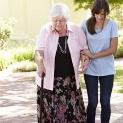 Leben im Alter: Eine Frau bei einem Spaziergang mit einer Seniorin durch den Park