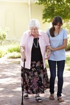Leben im Alter: Eine Frau bei einem Spaziergang mit einer Seniorin durch den Park