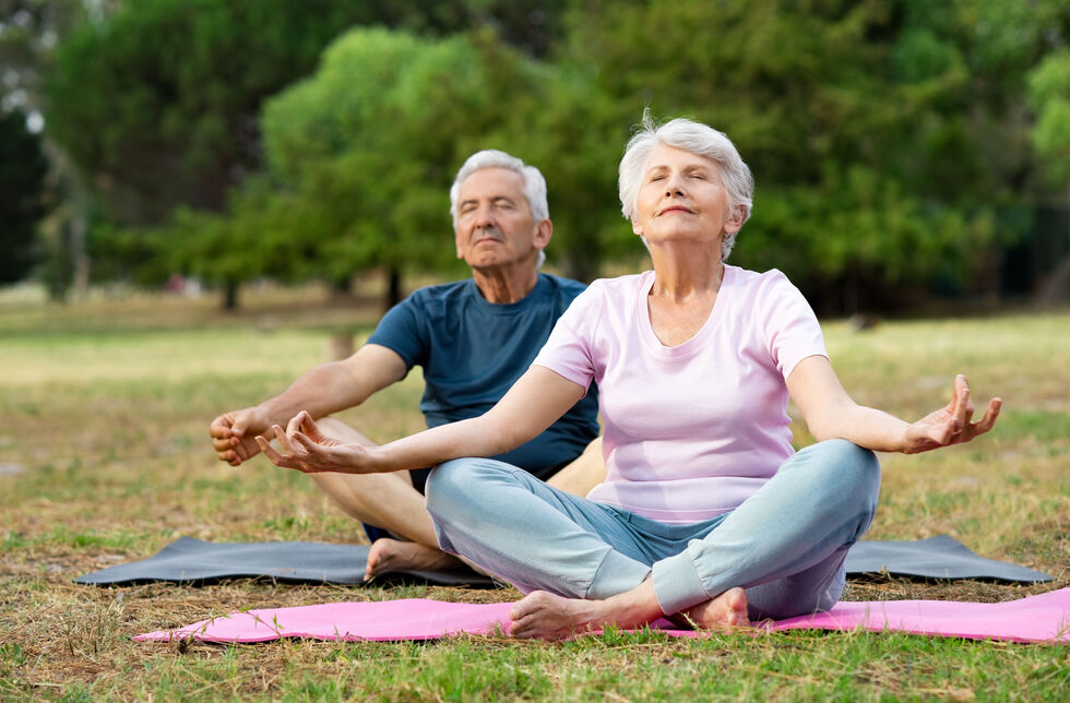 Zwei Senioren machen Yoga im Park