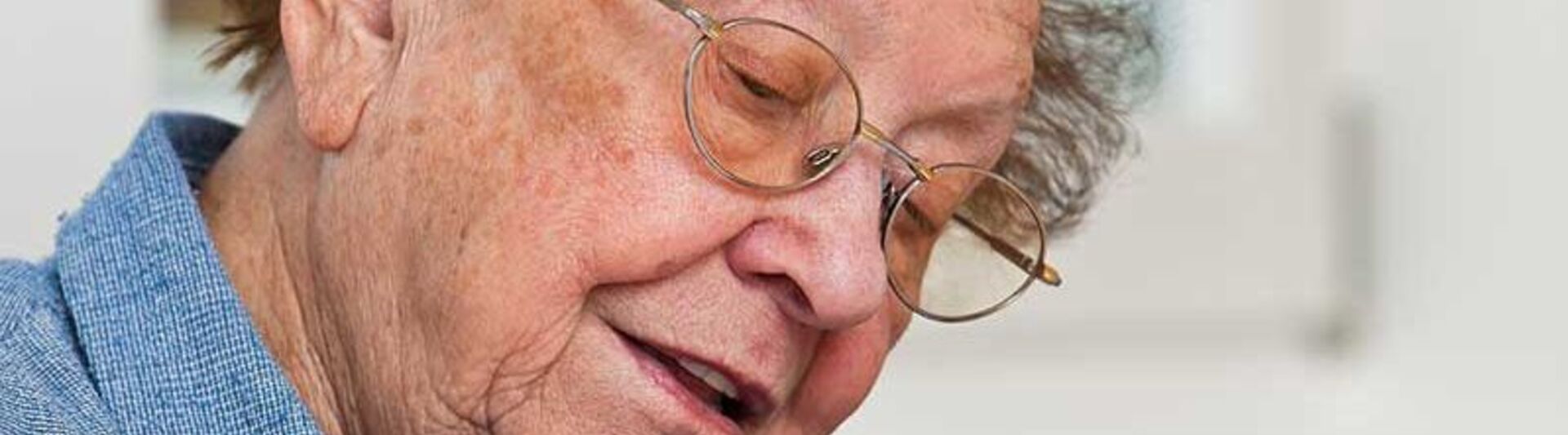 Senior sitzt in einer grünen Küche und denkt nach