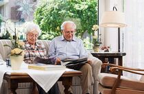 Älteres Paar sitzt auf dem Sofa und liest Zeitung