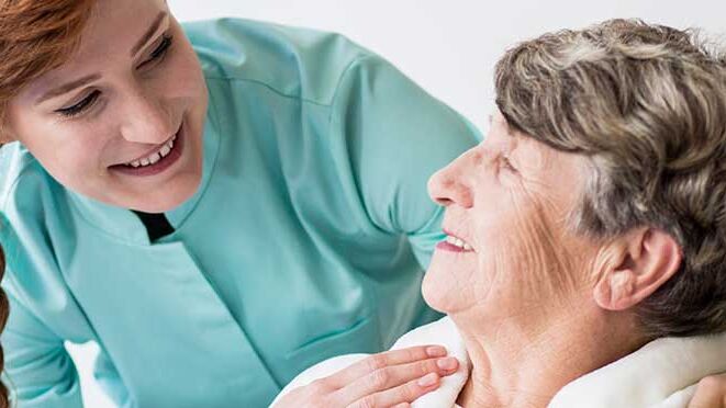 Pflegerin lächelt Patientin an