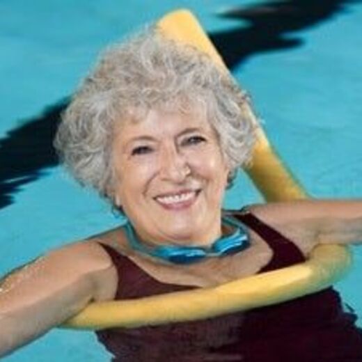 Seniorin ist mit Schwimmnudel im Wasser