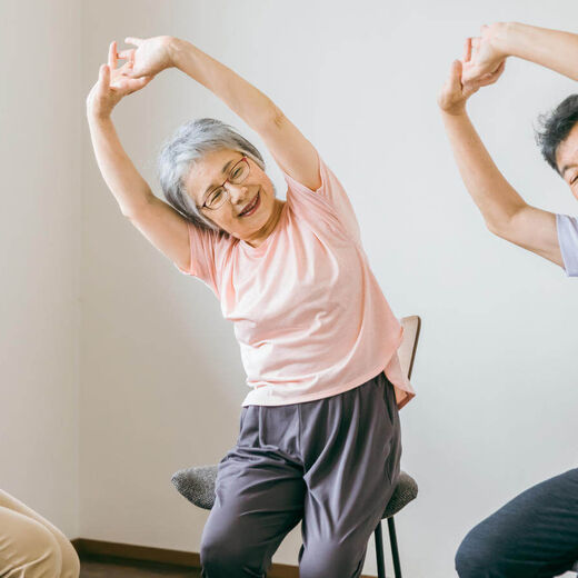 Seniorenpaar führt gemeinsam mit Therapeutin Gymnastikübungen im Sitzen durch. © buritora - stock.adobe.com