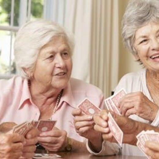 Seniorengruppe spielt lachend mit Karten