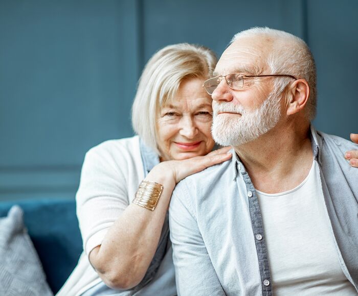 Älteres Paar sitzt auf dem Sofa und umarmt sich