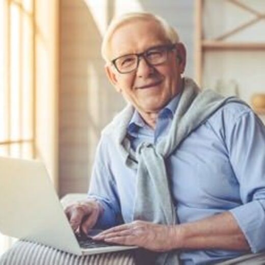 Senior mit Brille sitzt am Laptop