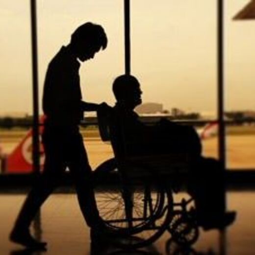 Rollstuhlfahrer wird über den Flughafen geschoben