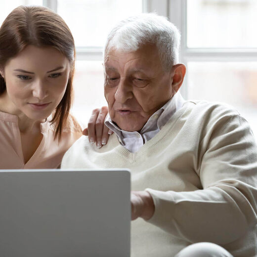 Senior und Tochter vergleichen Hausnotruf-Anbieter am Laptop.