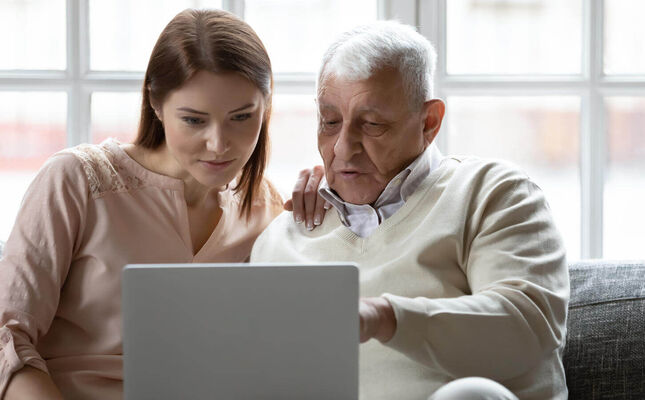 Senior und Tochter vergleichen Hausnotruf-Anbieter am Laptop. © fizkes - stock.adobe.com