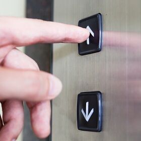 Aufzugknöpfe für einen Senkrechtlift Person drückt einen Knopf um den Senkrechtlift zu rufen