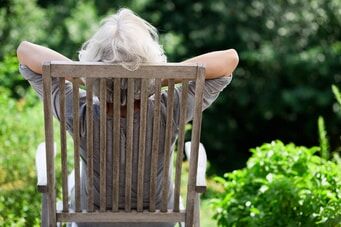 Alte Dame entspannt auf einem Gartenstuhl