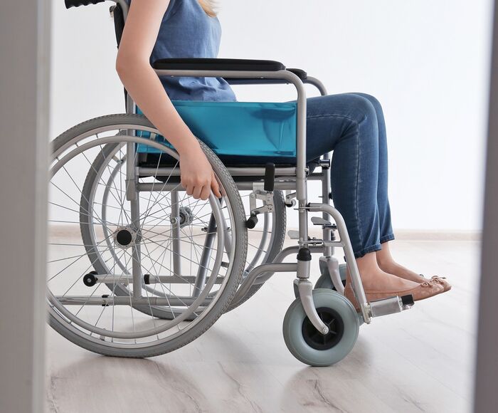 Frau im Rollstuhl schaut aus dem Fenster