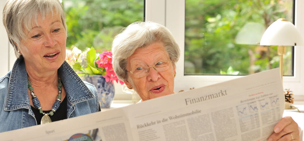Zwei Rentnerinnen lesen die Zeitung und sind erstaunt über den Inhalt