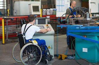 Rechte bei Behinderung: Ein Rollstuhlfahrer und sein Kollege bei der Arbeit in der Werkstatt