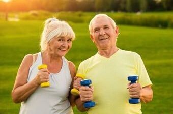 Seniorenpaar macht Sport im Garten mit Hanteln