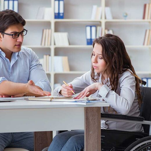 Zuschüsse für Menschen mit Behinderung: Rollstuhlfahrerin mit Kollegen im Büro