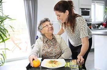 Betreutes Wohnen im Alter: Eine Pflegerin kümmert sich um eine Seniorin