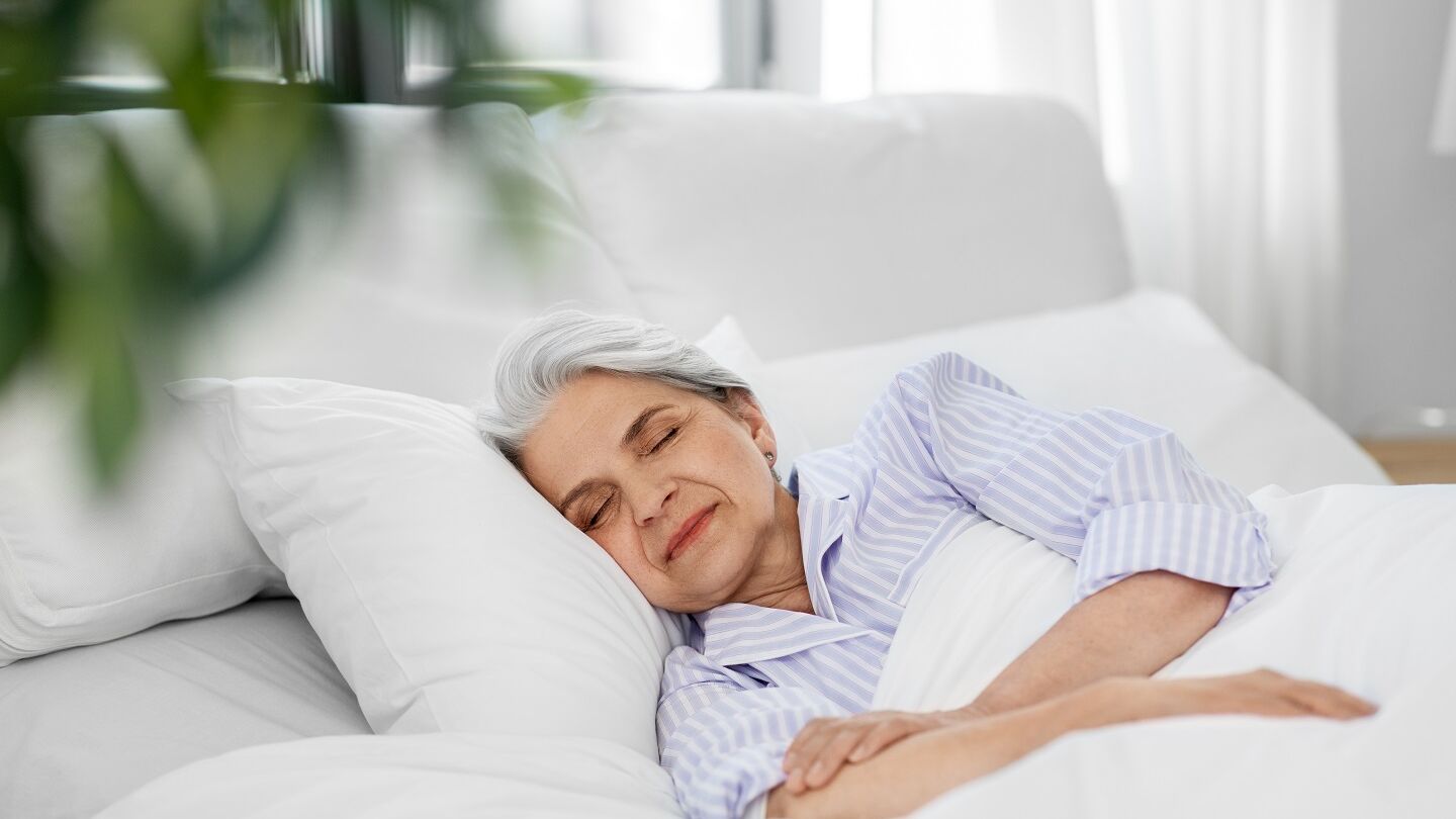 Schlafende Seniorin im Bett Frau liegt zufrieden im Bett und schläft