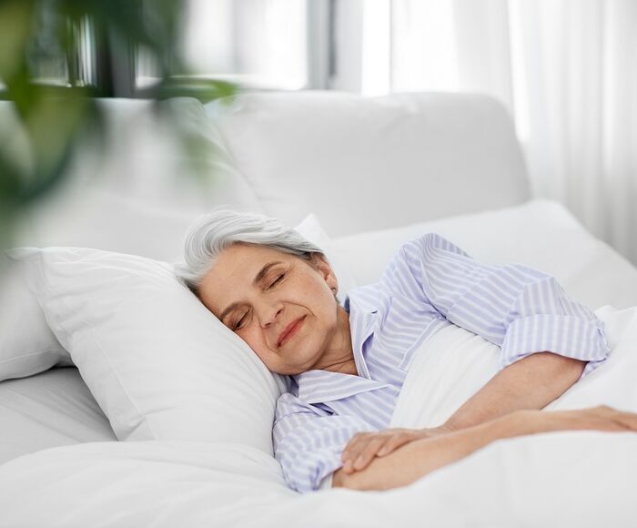 Frau liegt zufrieden im Bett und schläft