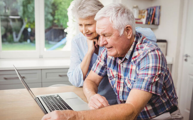 Treppenlift-Ratgeber: Älteres Ehepaar durchstöbert das Internet auf ihrem Laptop nach passenden Anbietern