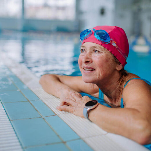 Seniorin am Beckenrand legt Pause vom Schwimmen ein.
