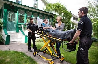 Erste Hilfe für Senioren in Notfallsituationen Erste Hilfe für Senioren: Sanitäter kümmern sich um eine Seniorin auf einer Trage