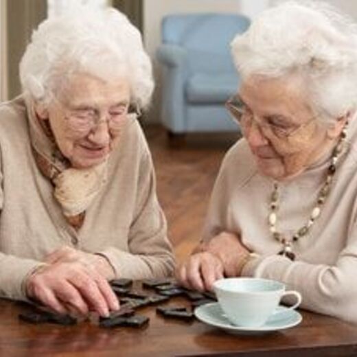 Zwei Seniorinnen spielen Domino bei einem Kaffee