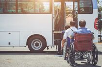 Barrierefrei Reisen: Eine Reisegruppe in Rollstühlen vor einem Bus