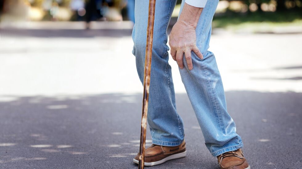 Älterer Herr greift sich ans Knie wegen Schmerzen