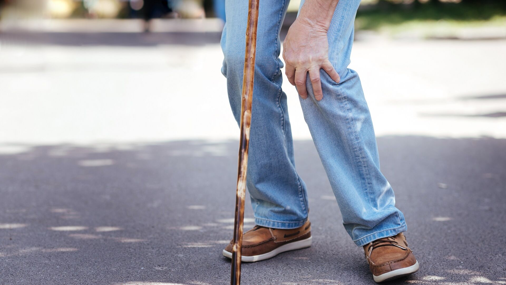 Älterer Herr greift sich ans Knie wegen Schmerzen