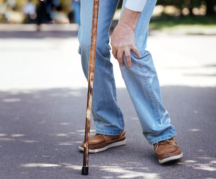 Älterer Herr greift sich ans Knie wegen Schmerzen