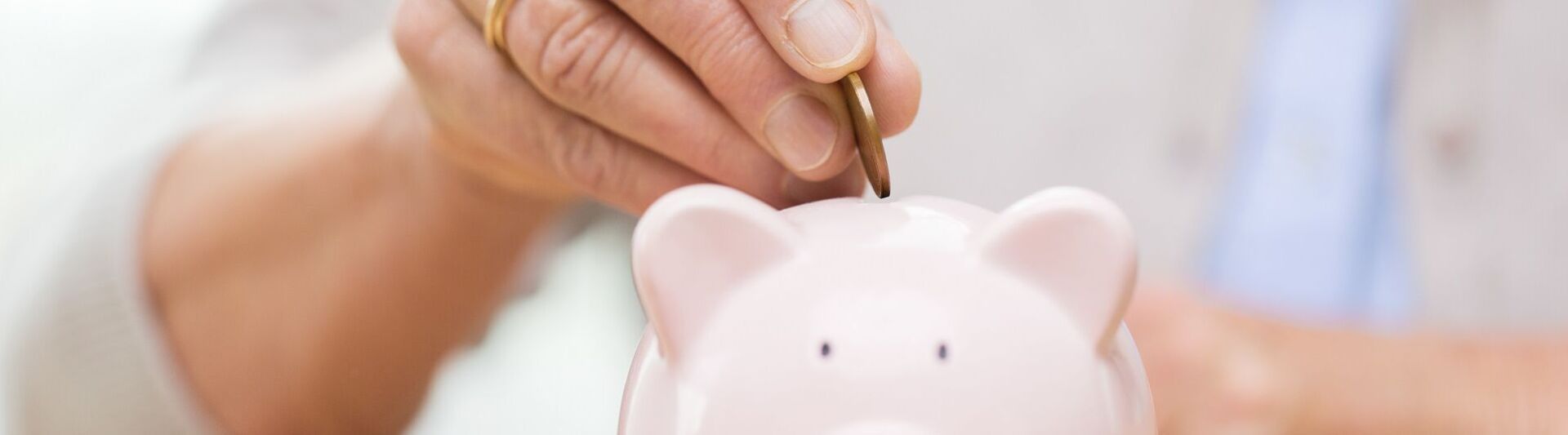 Geld zurücklegen Hand wirft Münzen in ein Sparschwein