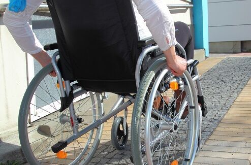 Treppenlifte für Institutionen: Ein Rollstuhlfahrer auf seinem Weg zum Gebäude