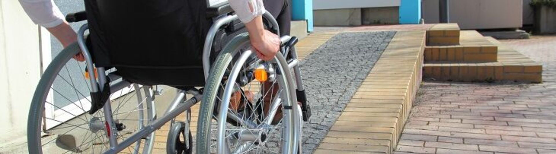 Treppenlifte für Institutionen: Ein Rollstuhlfahrer auf seinem Weg zum Gebäude