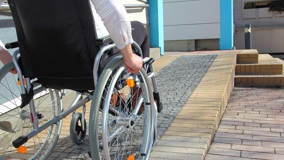 Treppenlifte für Institutionen: Ein Rollstuhlfahrer auf seinem Weg zum Gebäude
