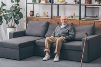 Senior sitzt auf seinem großen Sofa