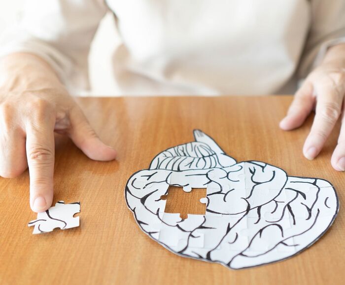Frau löst ein Puzzle in Form eines Gehirns