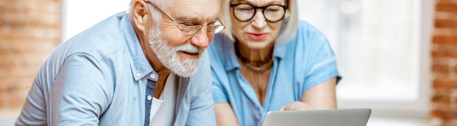 Ein Senior und seine Angehörige schauen auf einen Laptop zum Modellvergleich von Treppenliften