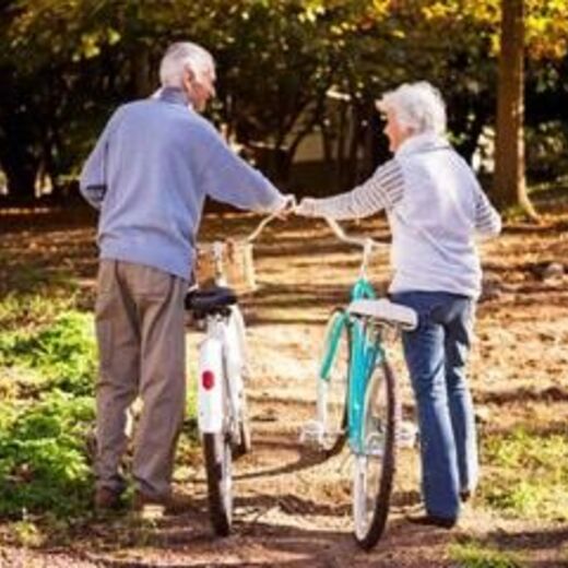 Seniorenpaar schiebt ihre Fahrräder durch den Wald