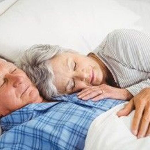 Seniorenpaar liegt kuschelnd im Bett